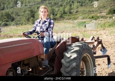 Agricoltore donna che lavora su un trattore agricolo Foto Stock