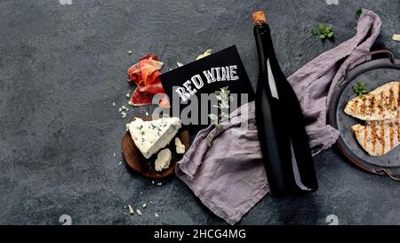 Sirah vino rosso con antipasti su sfondo grigio. Bevande alcoliche tradizionali. Vista dall'alto, disposizione piatta, spazio di copia Foto Stock
