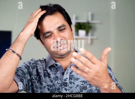 Preoccupato giovane uomo preoccupato per i capelli bianchi o la perdita di capelli dopo aver visto i capelli a portata di mano - concetto di alopecia , cura dei capelli e problema di forfora Foto Stock