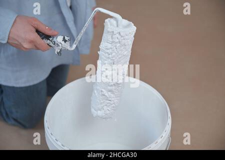 Primo piano di un operatore professionale che tiene una mano sporca rullo di vernice. Foto Stock