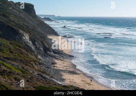 Solitario passeggiando sulla spiaggia di Praia da Amoreira lungo il surf, Algarve, Portogallo. Foto Stock