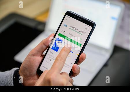 Seoul, Corea del Sud - 29 dicembre 2021: La mano di un uomo che installa un'app per smartphone per l'adeguamento fiscale di fine anno. Foto Stock