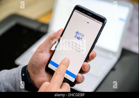 Seoul, Corea del Sud - 29 dicembre 2021: La mano di un uomo che installa un'app per smartphone per l'adeguamento fiscale di fine anno. Foto Stock