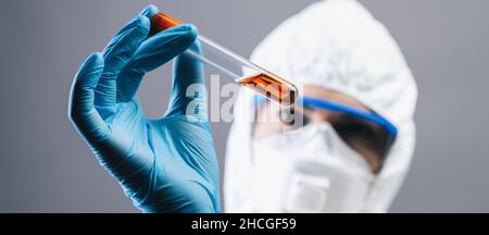Lavoratore di laboratorio medico femminile con provetta per analisi del sangue da 2019-nCoV Coronavirus. Campione di sangue positivo nella mano dello scienziato. Rottura coronavirus, dimensione banner Foto Stock