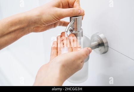 mani con dispenser per gel igienizzante per mani di lavaggio. Disinfettante trasparente in flacone per pompa, per eliminare germi, batteri e virus. Foto Stock