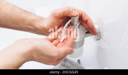 Man mani con dispenser per pompa igienizzante per mani lavabile. Igienizzatore trasparente in flacone per pompare, per l'abbattimento di germi, batteri e virus. Foto Stock