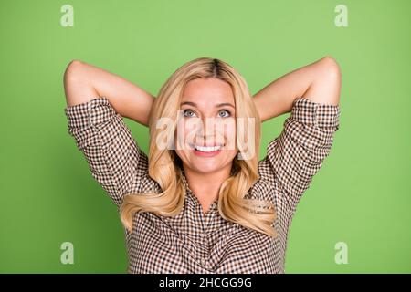 Ritratto di attraente sognante donna allegra che riposa indossando la camicia controllata isolato su sfondo di colore verde brillante Foto Stock