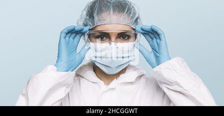 Medico o infermiere donna che indossa guanti protettivi in lattice e maschera medica protettiva e occhiali sul viso. Protezione per Coronavirus COVID-19 Foto Stock