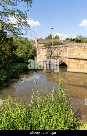 Il Fiume Windrush che scorre sotto il vecchio ponte in pietra del Cotswold città di Burford, Oxfordshire, Regno Unito Foto Stock