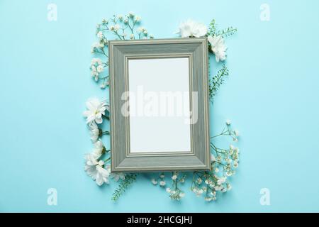 Cornice fotografica vuota con fiori su sfondo blu Foto Stock