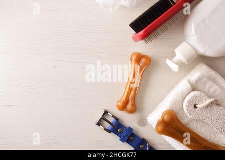 Igiene canina di cappotto, corpo e denti con prodotti su tavola bianca in legno. Vista dall'alto. Composizione orizzontale. Foto Stock