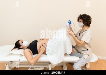 Ginecologo in possesso di un apparato muscolo pelvico del pavimento esercizio per preparare per la nascita di una donna sdraiata Foto Stock