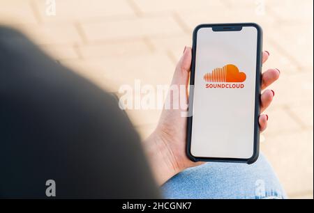 Donna con iPhone X che apre soundcloud Music streaming app in città. Streaming di musica tramite Internet Foto Stock