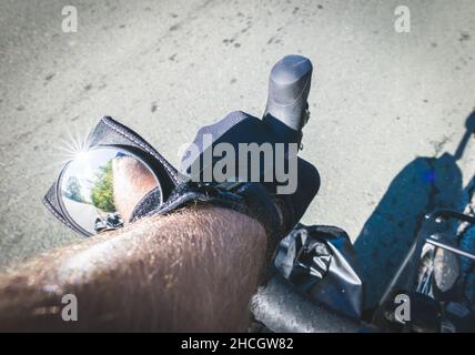 I ciclisti mano sul manubrio con uno specchio sul polso con una vista posteriore. Tour in bicicletta e pendolarismo e sicurezza sulle strade concetto. Foto Stock