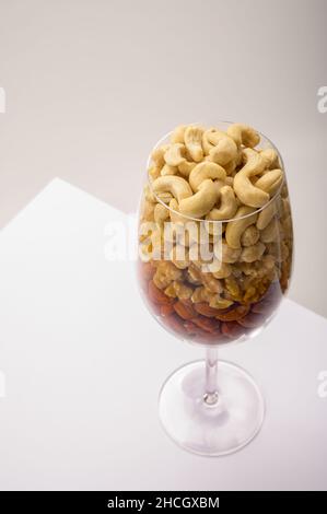 Vaso di vetro riempito con una varietà di nutrizione e snack sani e noci su uno sfondo bianco Foto Stock