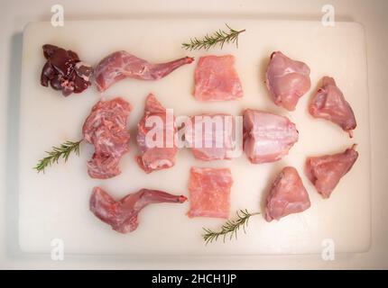 Coniglio crudo tagliato su un tagliere bianco. Vista dall'alto, disposizione piatta, primo piano. Foto Stock