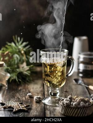 Processo di preparazione del tè. Una tazza di tè verde di provenienza fresca con bolle e vapore su sfondo di legno Foto Stock