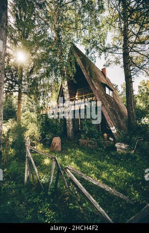 Una vista verticale di una capanna di ranger triangolare nel mezzo della foresta di taiga. Una vista prospettica di un casolare rurale indipendente estate nei boschi su un Foto Stock