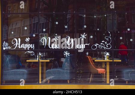 Londra, Regno Unito 29th dicembre 2021. Un cartello "Happy New Year" sulla finestra di un ristorante chiuso nel West End di Londra. Nonostante la mancanza di nuove restrizioni, molti ristoranti hanno segnalato un calo dei clienti a causa della diffusione della variante Omicron del coronavirus. Credit: Vuk Valcic / Alamy Live News Foto Stock