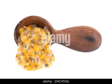 Semi di frutto della passione in cucchiaio di legno, isolato su sfondo bianco. Polpa di passionfrutto o maracuya, frutta esotica. Foto Stock