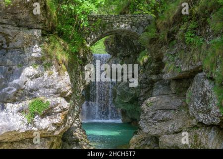Cascata Rio Repepeit una piccola cascata artificiale con ponte di pietra, CHIUSAFORTE, provincia di Udine, Italia Foto Stock