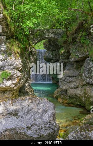 Cascata Rio Repepeit una piccola cascata artificiale con ponte di pietra, CHIUSAFORTE, provincia di Udine, Italia Foto Stock