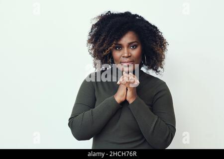 Bella donna sorridente di mezza età Black African American con capelli ricci e mani aggrappate Foto Stock