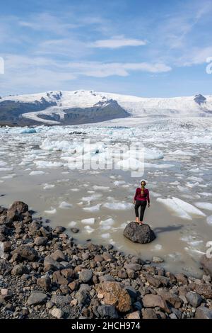 Donna di fronte alla laguna di ghiaccio Fjallsarlon, ghiaccio galleggianti di fronte al ghiacciaio Vatnajoekull, Hornafjoerour, Islanda Foto Stock