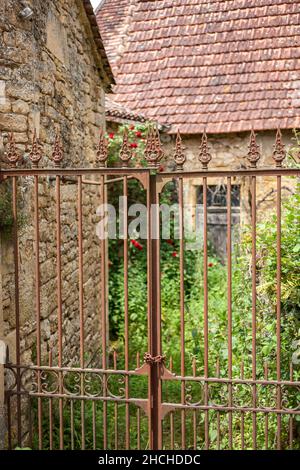 Vecchio cancello di metallo arrugginito con un vecchio edificio di pietra nel campo da background Foto Stock