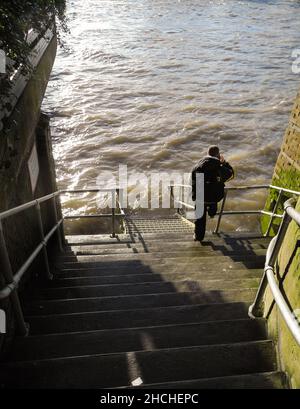 Un uomo in profonda contemplazione alla base di Cousin Lane Scale alla fine di Cousin Lane che conduce fino al Tamigi, Londra, Inghilterra, Regno Unito Foto Stock