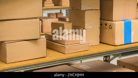 Scatole di cartone diverse su scaffali in un magazzino, immagine del concetto di consegna corriere imballato Foto Stock