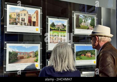Coppia più anziana che guarda nella finestra dell'ufficio immobiliare alle descrizioni della proprietà, Regno Unito Foto Stock