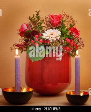 Primo piano di un bouquet di fiori in vaso e due candele Foto Stock