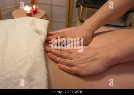 Massaggio rilassante alla schiena sdraiato su un pullman con un asciugamano bianco in un salone spa Foto Stock