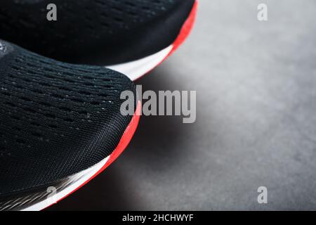 Scarpe da running nere con rete e lacci neri da vicino su sfondo scuro. Vista dall'alto delle sneaker sportive. Foto Stock