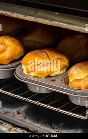 Budini dello Yorkshire individuali che cucinano in un forno elettrico. Cucina tradizionale britannica Foto Stock