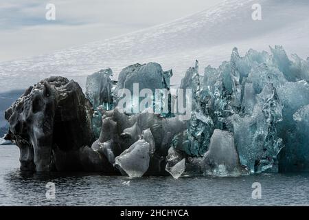 Una foto di un iceberg che mostra ghiaccio chiaro, blu e nero con sfondo montagna in Paradise Bay, Antartide Foto Stock