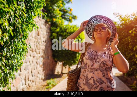 Donna anziana in pensione che cammina sul territorio dell'hotel nel parco. Vacanze estive in Egitto. Ritratto di elegante signora alla moda Foto Stock