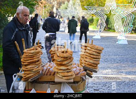 Atene, Grecia - 21 dicembre 2019: Venditore di strada sconosciuto che vende tradizionali bagel di sesamo crispy cotti greci (Koulouri) sul Dionysiou Areopagitou Foto Stock