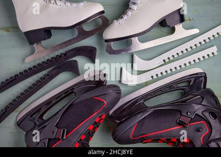 Pattinaggio su ghiaccio nero maschile e bianco femminile su sfondo di legno blu chiaro. Intrattenimento sportivo invernale. Vista dall'alto. Disposizione piatta Foto Stock