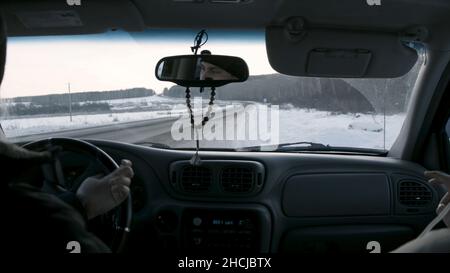 Interni auto e strada invernale. Riprese. Vista conducente e passeggero dal pozzetto di un'auto sulla strada innevata, vista posteriore p Foto Stock