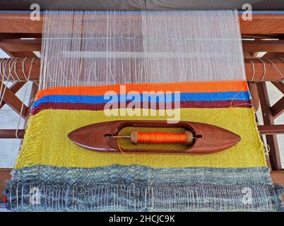 Fabbricazione di tessuto a strisce su un telaio manuale Foto Stock