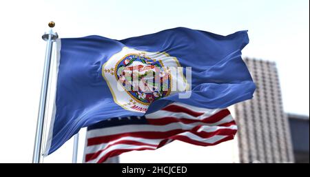 La bandiera dello stato del Minnesota degli Stati Uniti sventola nel vento con la bandiera americana sfocata sullo sfondo. Il Minnesota è stato ammesso all'Unione il mese di maggio Foto Stock