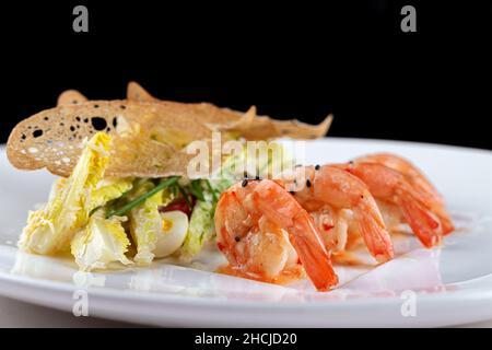 Gamberetti bolliti con lattuga, uova e pomodori ciliegini su un piatto bianco Foto Stock