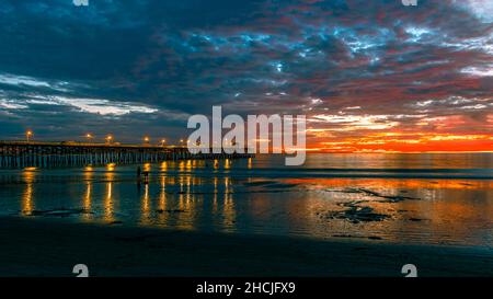 Bel molo sul lato dell'oceano al tramonto con luci sull'oceano Pacifico nuvoloso Foto Stock