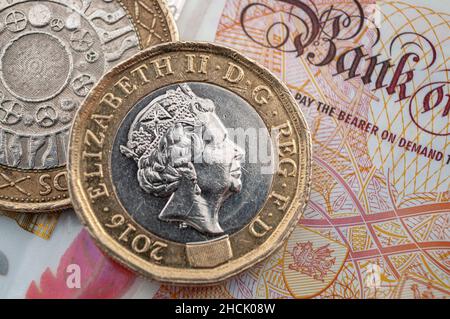 Business e finanza, economia britannica e cambio valuta concetto con macro primo piano su monete da 1 sterlina e due sterline e banconote da 10 GBP Foto Stock