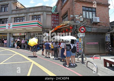 All'esterno dell'entrata della Jiufen Old Street a New Taipei City, Taiwan, con un minimarket Eleven del 7 e gente che fa la fila in un negozio di alimentari. Foto Stock