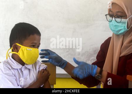 Tangerang, Indonesia. 30th Dic 2021. Un operatore sanitario somministra una dose di vaccino cinese Sinovac COVID-19 a un ragazzo durante la vaccinazione per bambini di età compresa tra i 6 e i 11 anni al villaggio di Cisauk a Tangerang, provincia di Banten, Indonesia, 30 dicembre 2021. Credit: Agung Kuncahya B./Xinhua/Alamy Live News Foto Stock