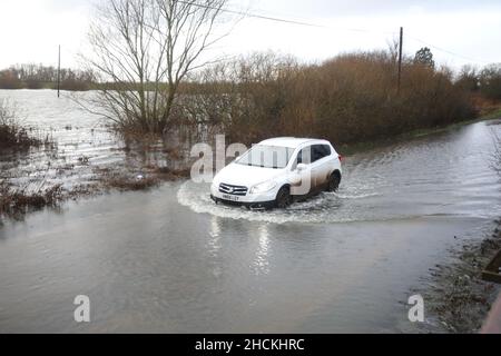 Sutton Gault, Regno Unito. 28th Dic 2021. Una persona guida attraverso la strada allagata a Sutton Gault. I livelli del fiume Great Ouse a Sutton Gault sono aumentati rapidamente nelle ultime 24 ore che hanno portato alle inondazioni in questa zona di Cambridge, il 28 dicembre 2021 Credit: Paul Marriott/Alamy Live News Foto Stock