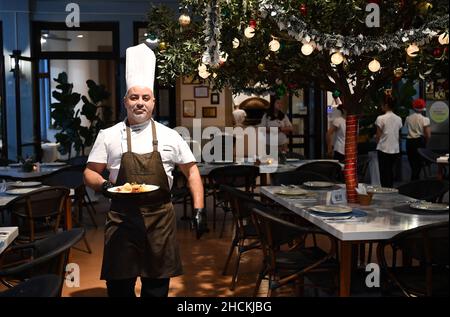 Sanya, la provincia cinese di Hainan. 28th Dic 2021. Daniele, proprietario e chef di un ristorante italiano, serve la cena al ristorante di Sanya, nella provincia di Hainan, nel sud della Cina, il 28 dicembre 2021. PER ANDARE CON 'Profilo: Lo chef italiano compie sogno in Cina isola resort ' Credit: Guo Cheng/Xinhua/Alamy Live News Foto Stock
